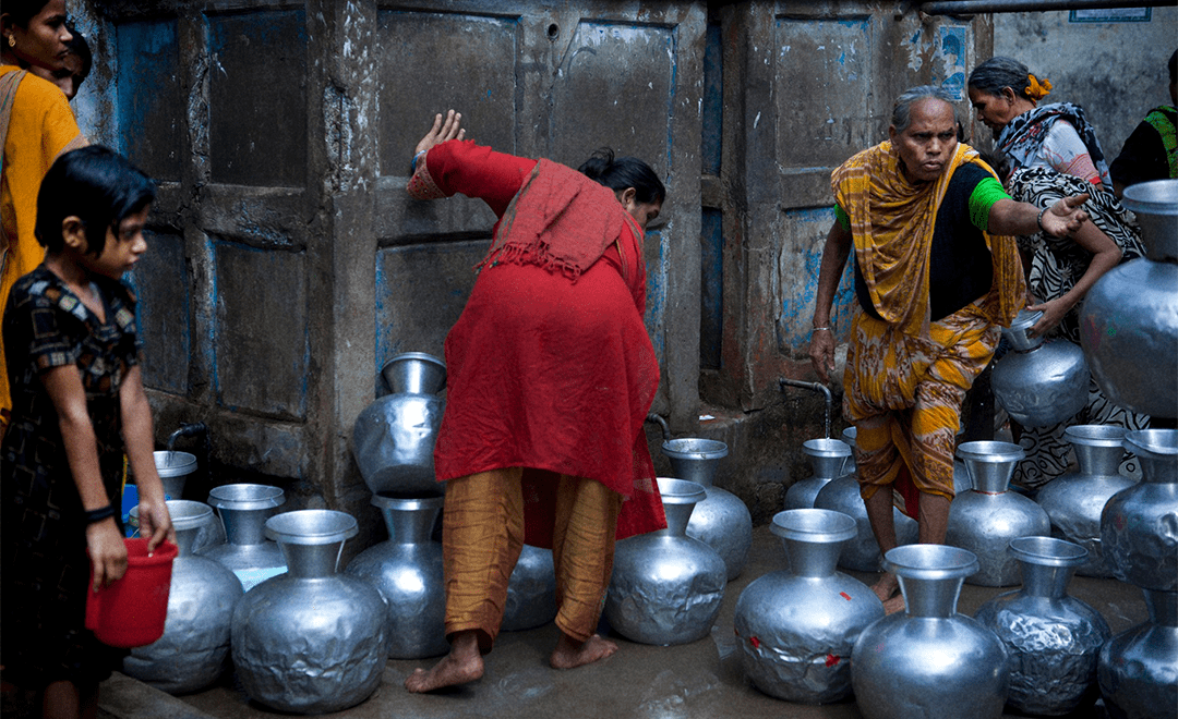 An image showcasing the trouble for water in India where differently aged women and trying to fill water