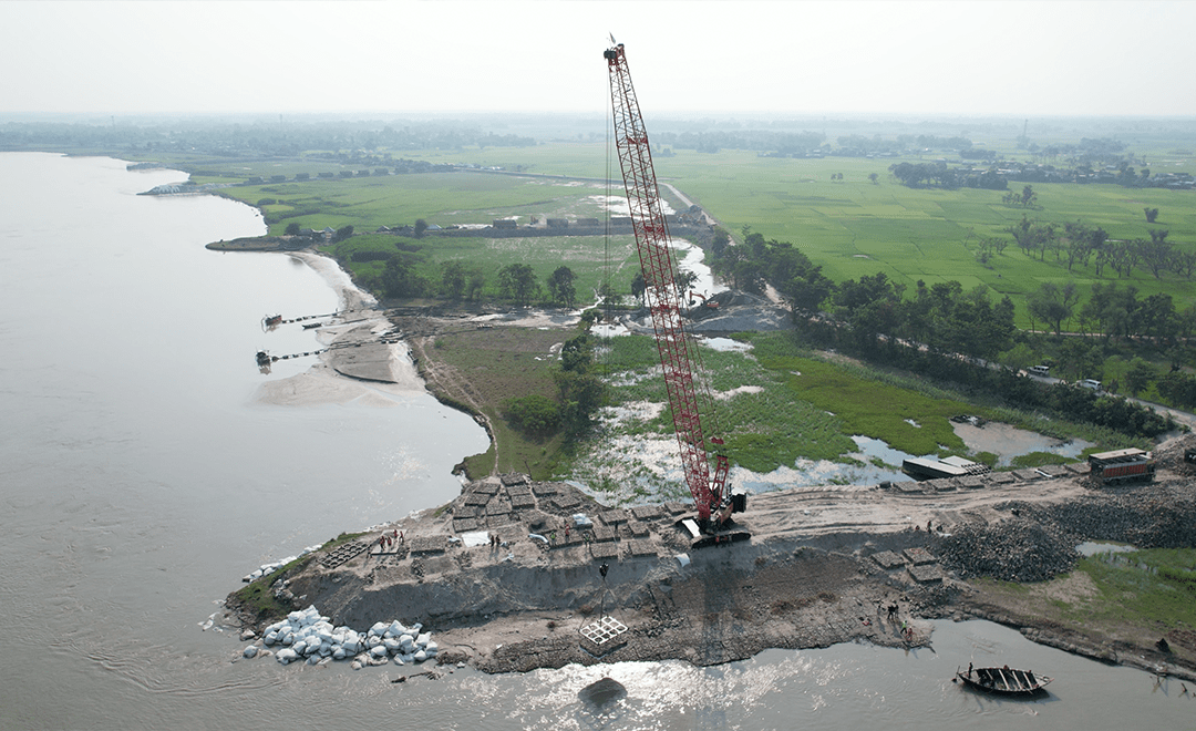A drone image which has a red crane working at the edge of a waterbody